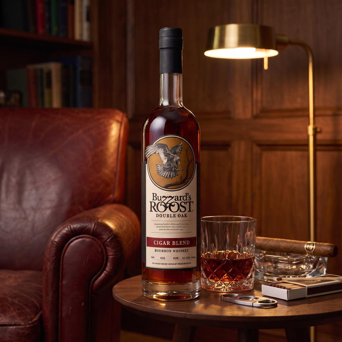 Buzzard's Roost Double Oak Cigar Blend Bourbon on a walnut side table by a leather club chair, with a neat pour, an unlit cigar and a cigar cutter