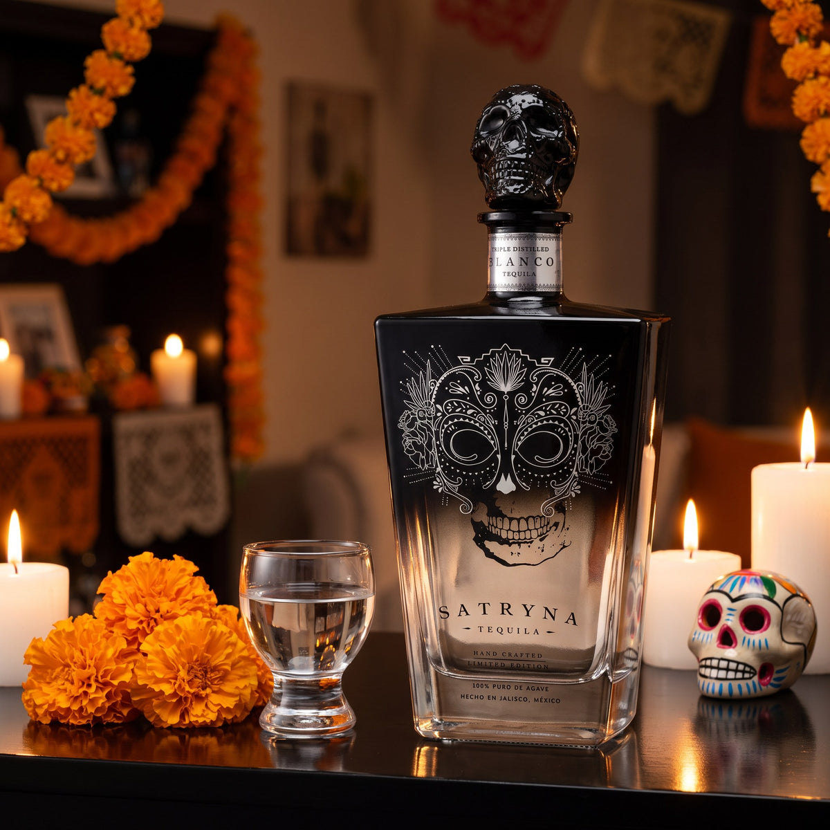 Satryna Tequila Blanco, 80 proof, on a black lacquered home bar with marigolds, candles and a painted sugar skull for Día de Muertos